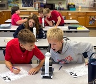 a middle school student using a microscope in science class
