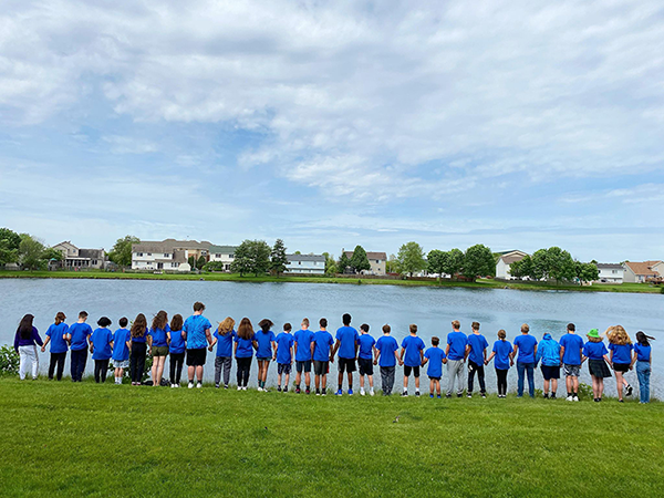 8th grade class praying together by the lake