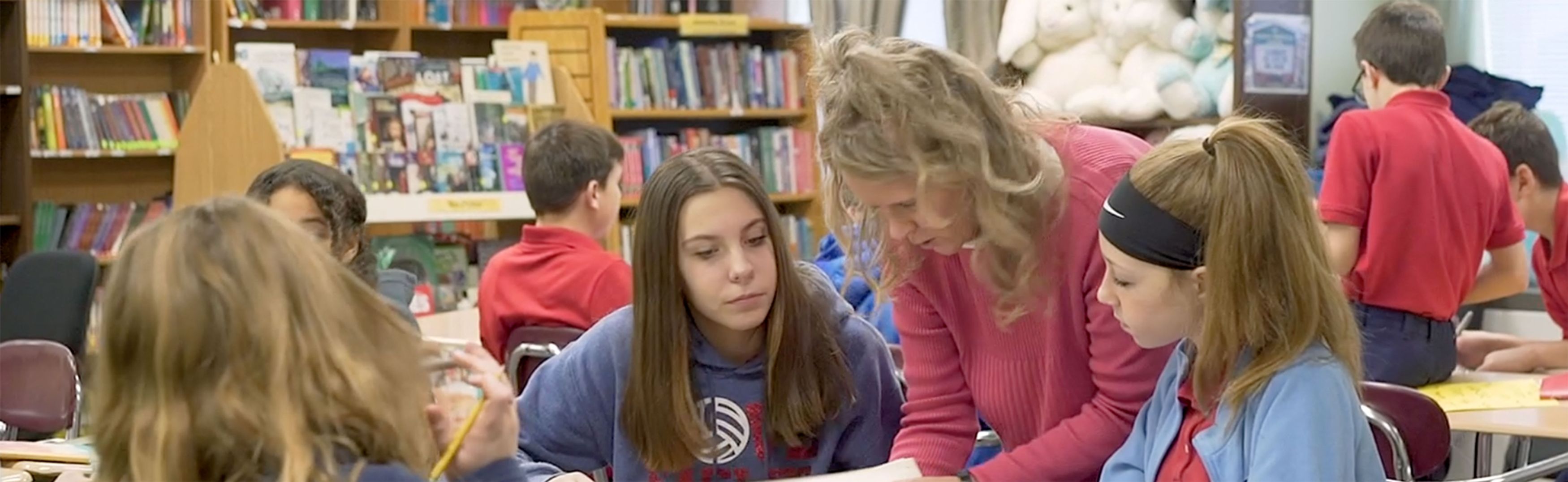A middle school teacher working with two students in her classroom